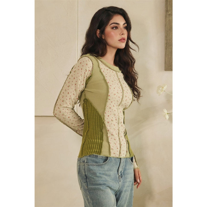 Woman wearing a green and beige top with a neutral background