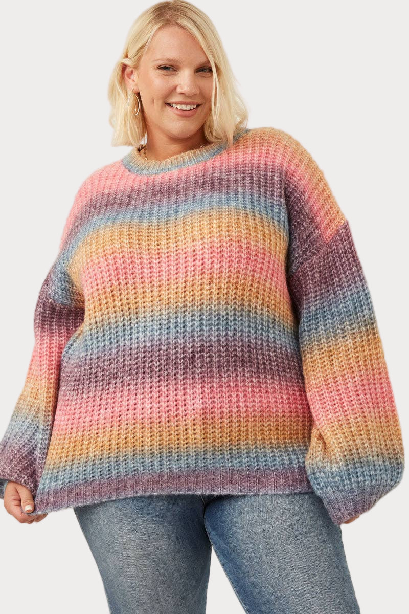 Plus Women wearing ombre striped chunky knit sweater in soft pink, blue, and golden tones—cozy and colorful fall outfit, sizes S–3X.