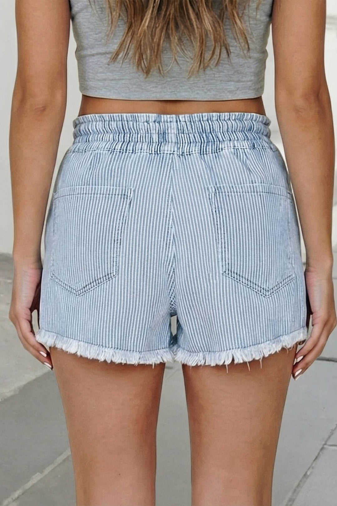 Light blue striped shorts worn by a person on a neutral background, showing back