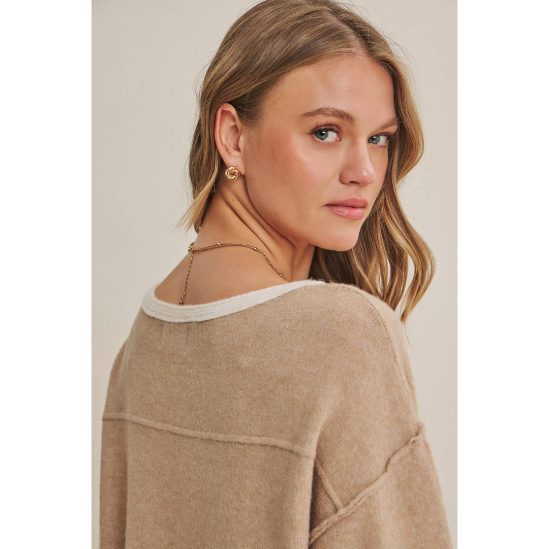 Woman wearing a beige sweater with a neutral background