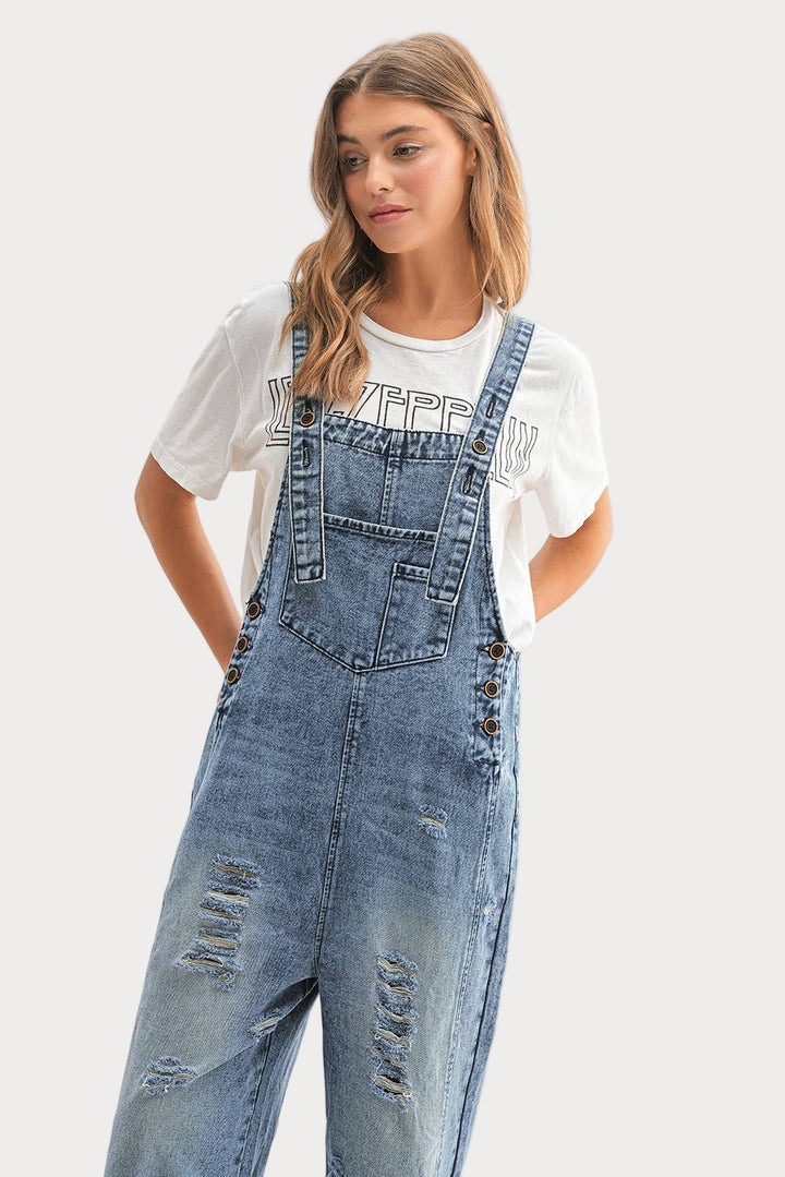 Person wearing denim overalls and a white t-shirt with text on a plain background