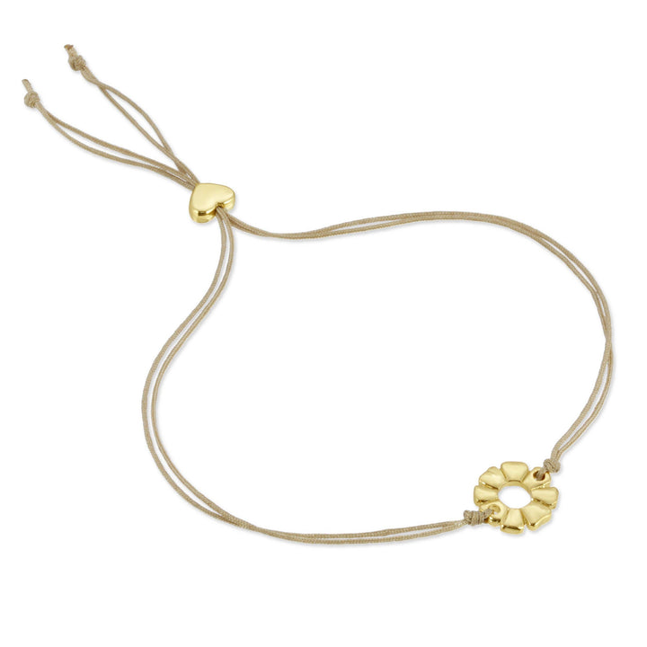 Bracelet with gold charm on a beige cord against a white background