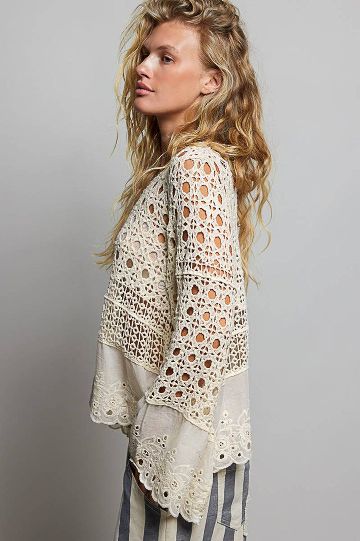Model wearing The Briar Rose Crochet Blouse featuring intricate open crochet, embroidered eyelet cotton panels, long bell sleeves, and a relaxed bohemian silhouette in ivory.