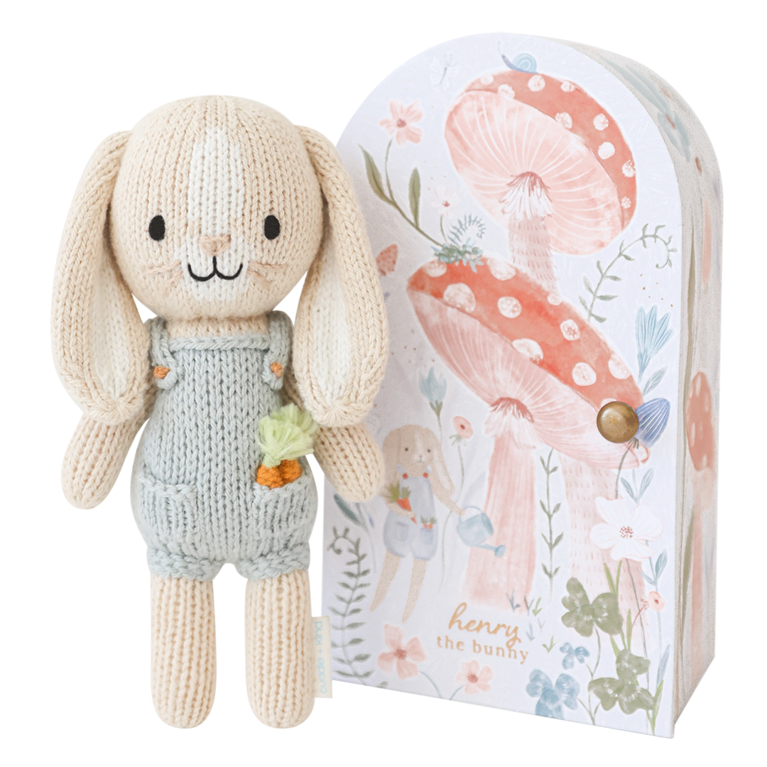Knitted bunny toy with a floral-themed packaging box on a white background