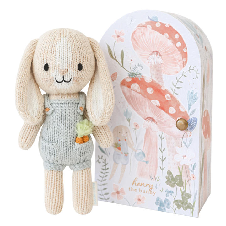 Knitted bunny toy with a floral-themed packaging box on a white background