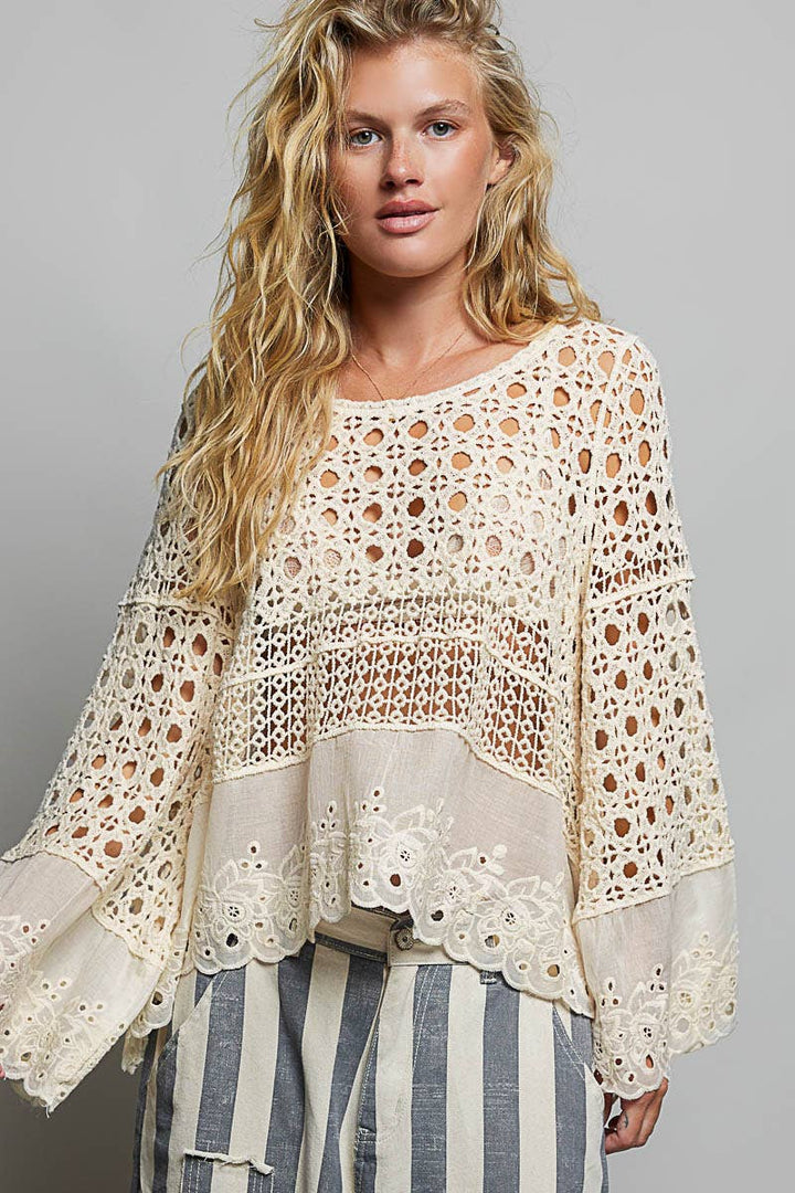 Model wearing The Briar Rose Crochet Blouse featuring intricate open crochet, embroidered eyelet cotton panels, long bell sleeves, and a relaxed bohemian silhouette in ivory.