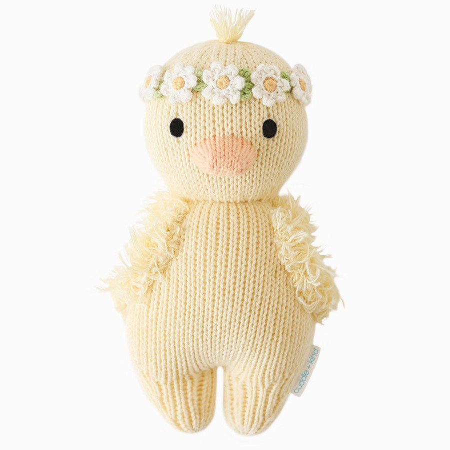 Knitted toy baby duck with a flower headband on a white background