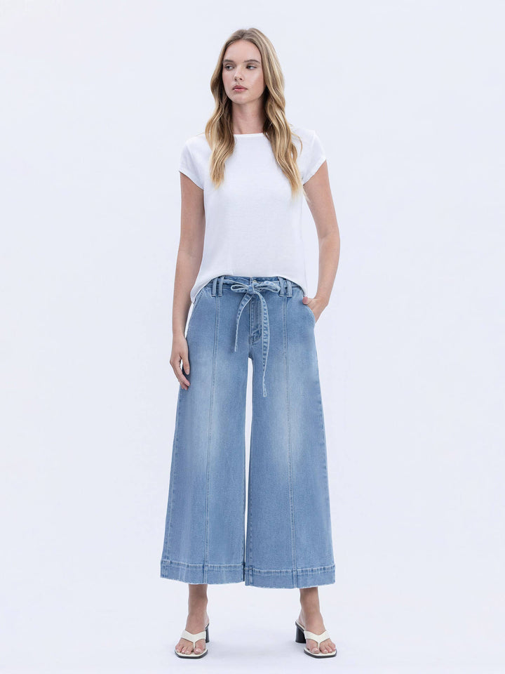 Woman wearing a white t-shirt and blue denim wide-leg pants on a white background