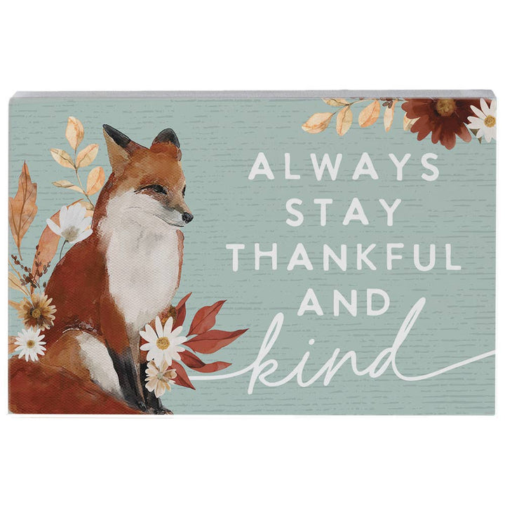 Decorative sign with a fox illustration and floral elements on a light blue background with 'Always Stay Thankful and Kind' text.