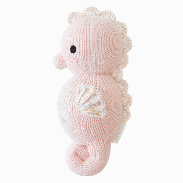 Knitted pink seahorse toy on a white background