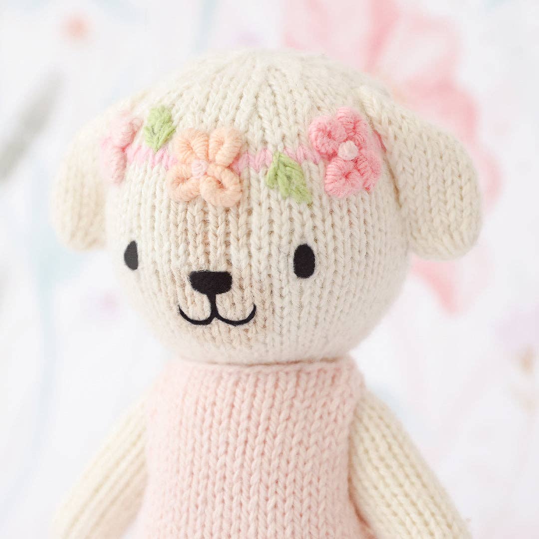Knitted dog with floral headband on a soft blurred background