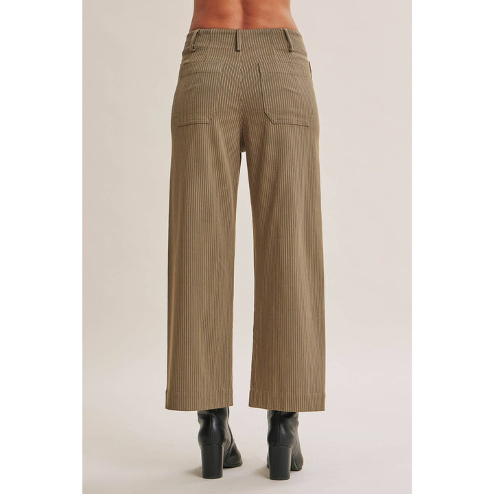 A person shown from the back wearing high-waisted, wide-leg cropped pants in a taupe-brown color with subtle vertical pinstripes, paired with black ankle boots against a light beige studio background.
