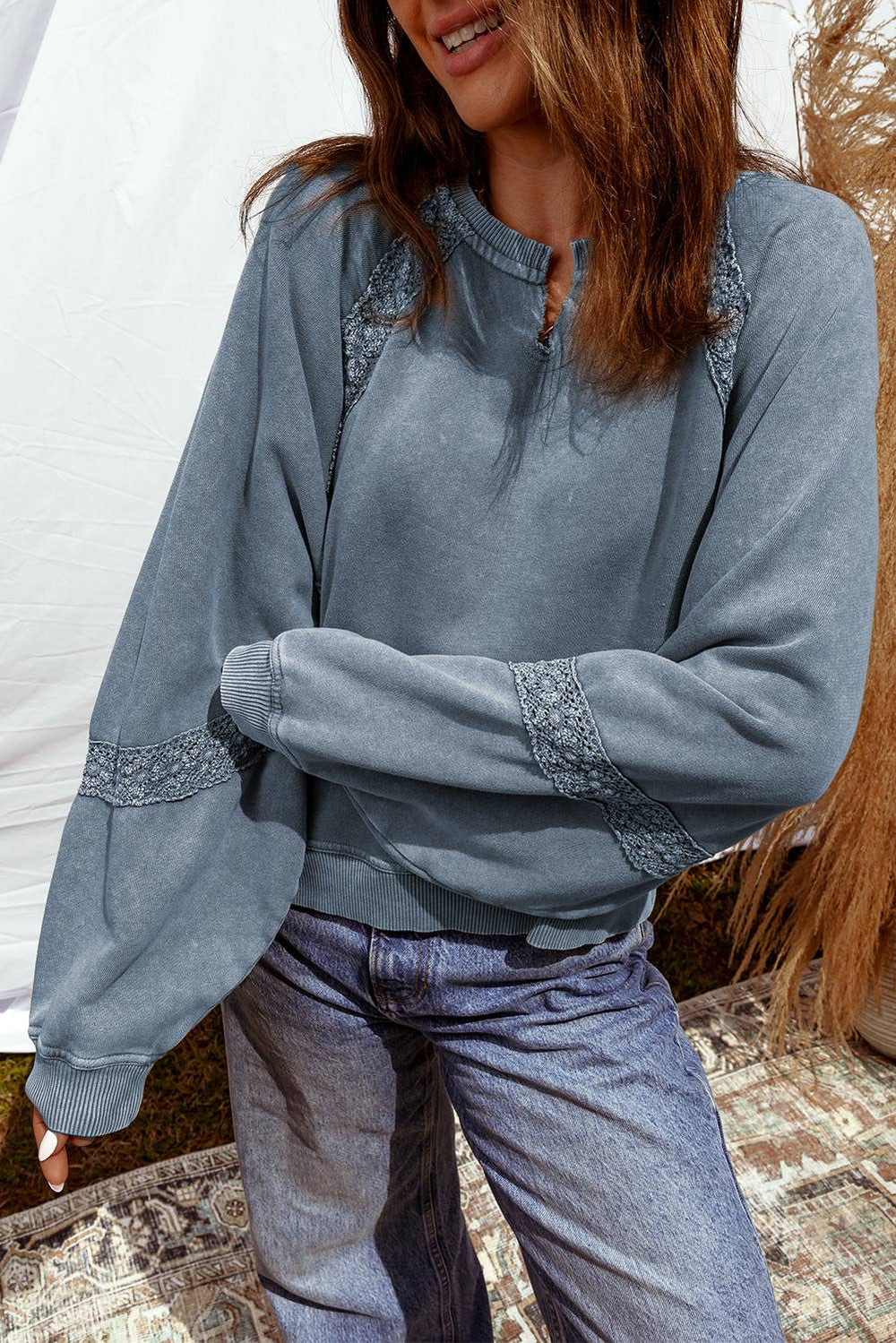 Woman wearing a vintage blue sweatshirt with lace trim details on shoulders and sleeves, styled with casual jeans.
