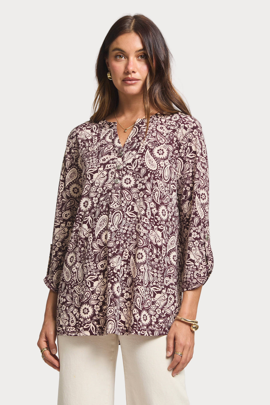 Woman wearing a patterned blouse against a plain background