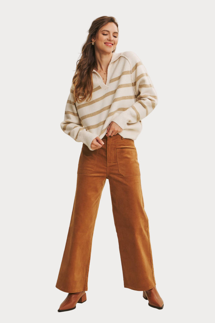 Woman wearing a striped sweater and brown pants on a beige background