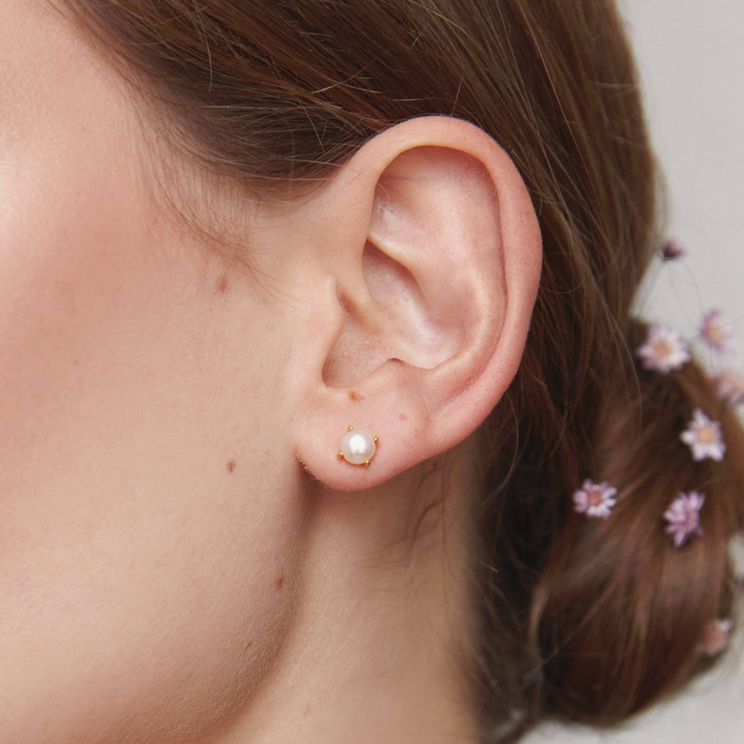 Close-up of an ear wearing a pearl earring with blurred background