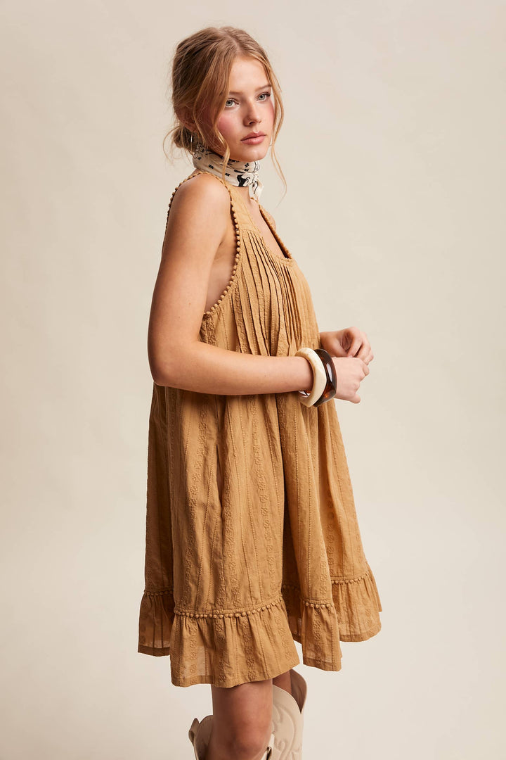 Woman wearing a camel colored dress against a beige background