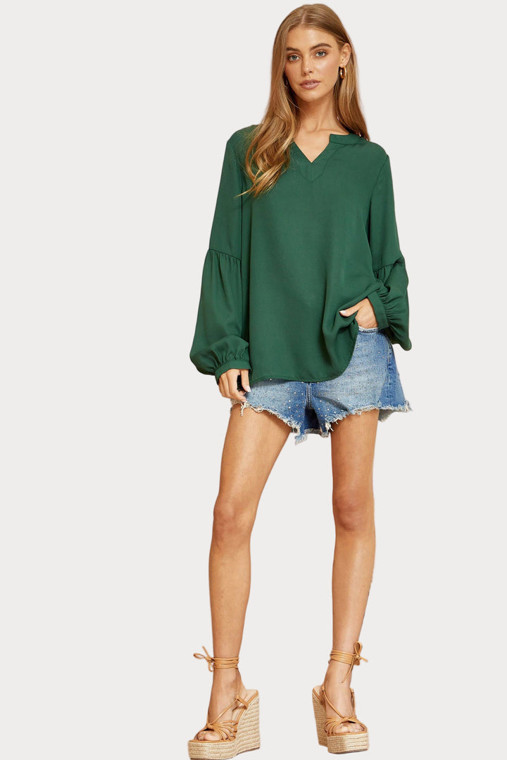 Woman wearing a green Blouse and denim shorts on a white background