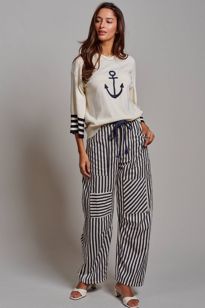 Woman wearing navy and ivory railroad stripe utility pants with oversized patch pockets, braided drawstring waist, and relaxed straight-leg fit.