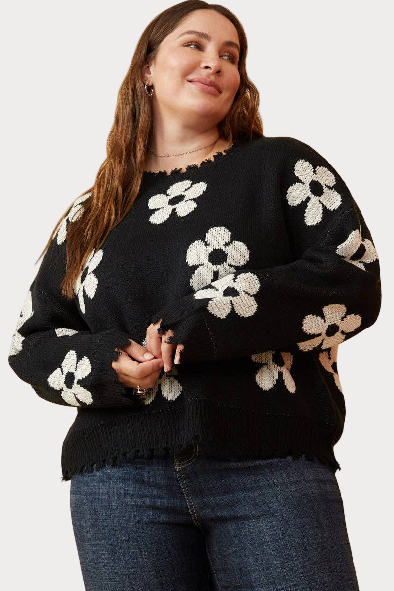 Women wearing black distressed floral pullover sweater with cream blooms—modern boho outfit, available in sizes S–3X.