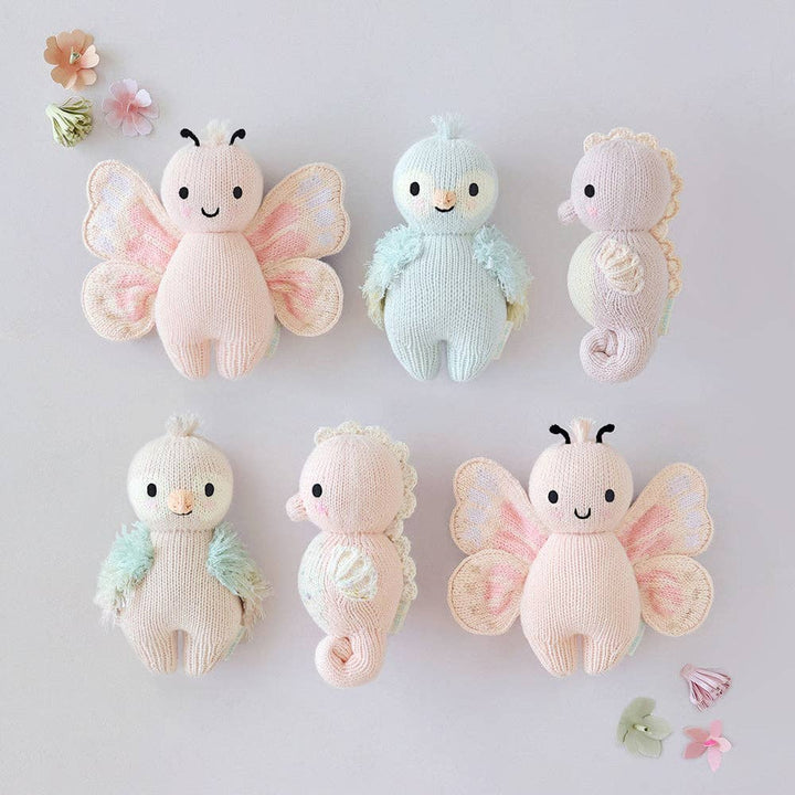 Set of soft toy animals including butterflies and a seahorse on a light gray background.