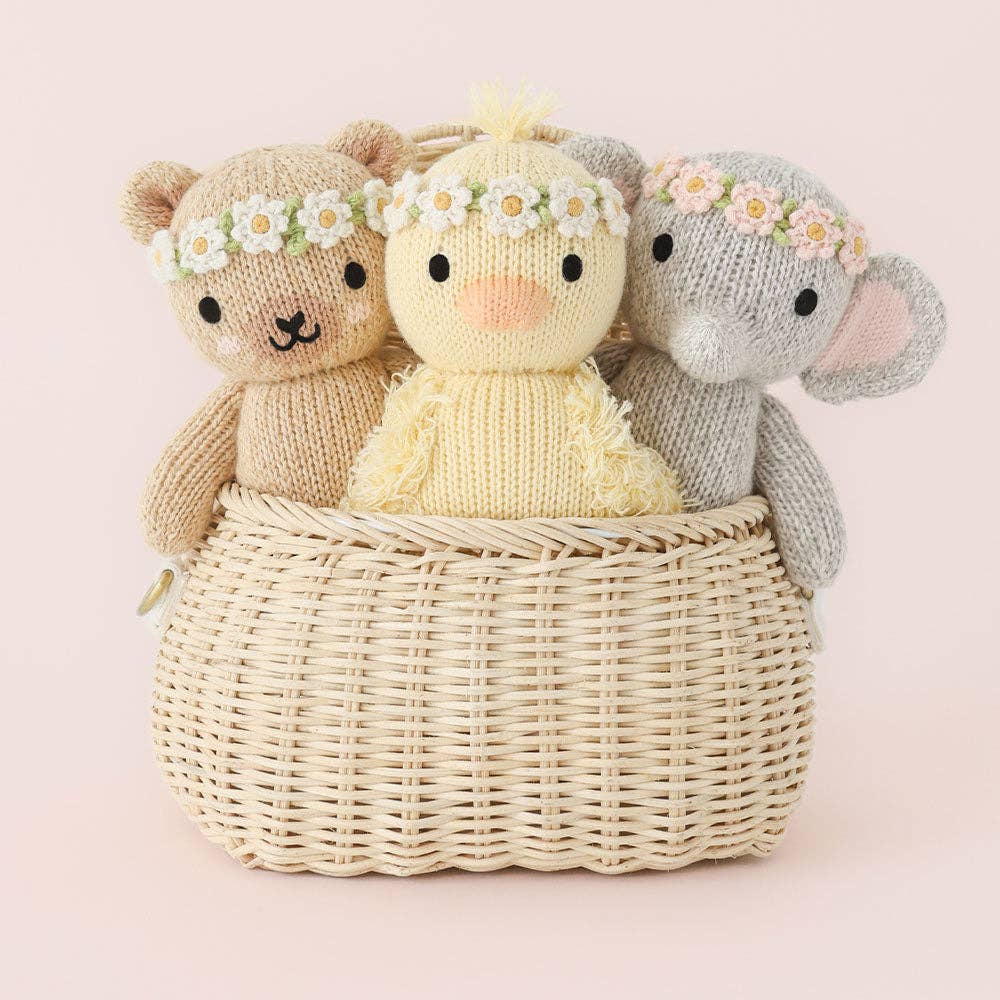 Baskey of knit plkush animals on soft pink background
