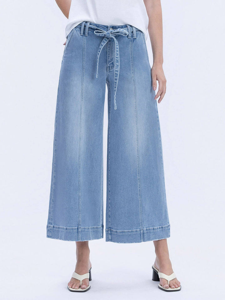 Light blue denim wide-leg pants with a tie waist on a white background