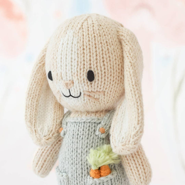 Knitted bunny toy with a carrot on a soft, blurred background