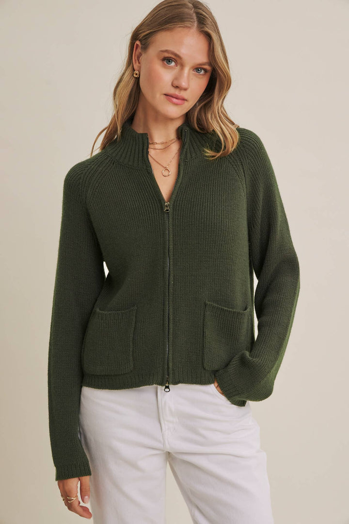 Woman wearing a green zip-up sweater against a beige background