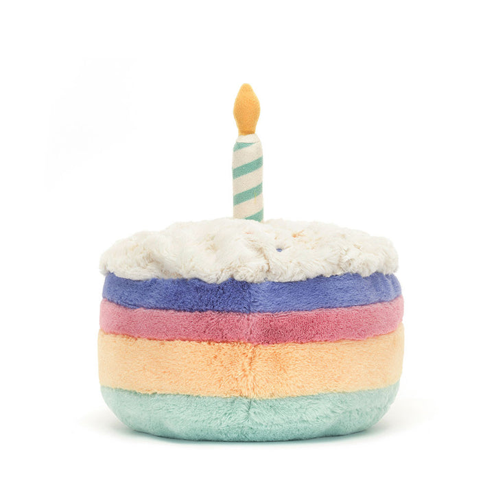 Multicolored rainbow plush toy resembling a birthday cake with a candle on a white background