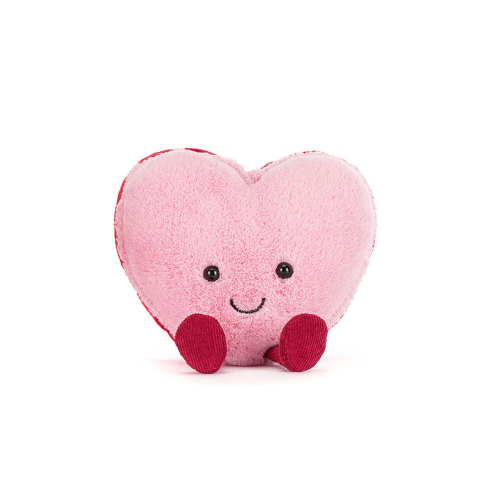 Pink heart-shaped macaron plush with smiling face and red corduroy feet