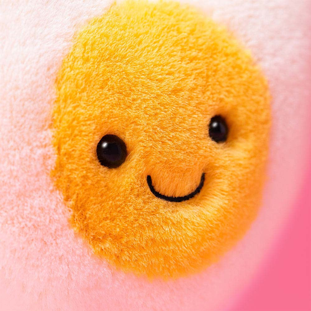 Closeup shot Jellycat Amuseables Heart Boiled Egg plush with cream heart shape, yellow center, stitched smile, 