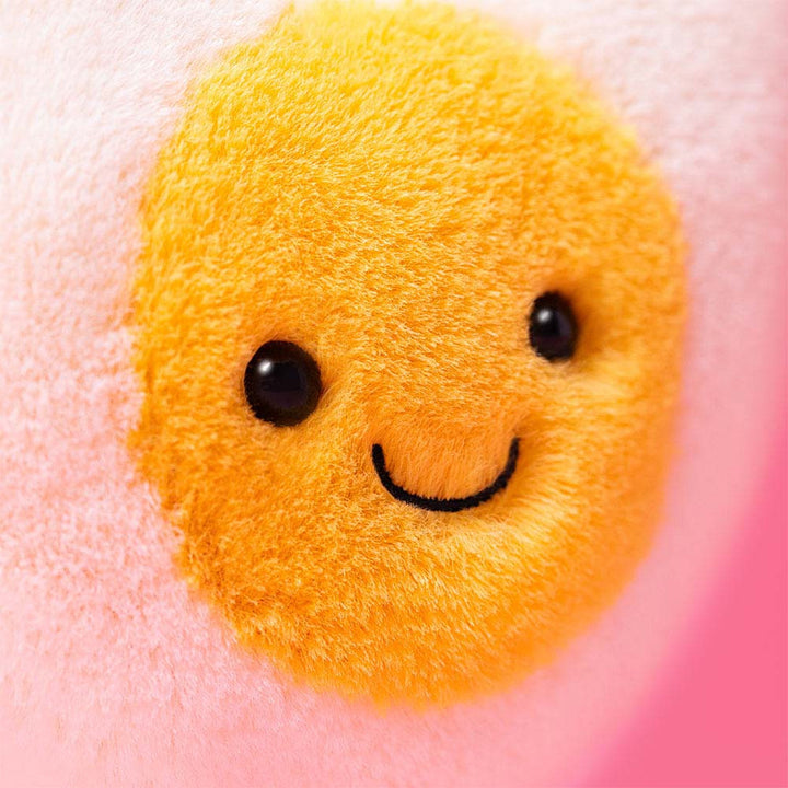 Closeup shot Jellycat Amuseables Heart Boiled Egg plush with cream heart shape, yellow center, stitched smile, 