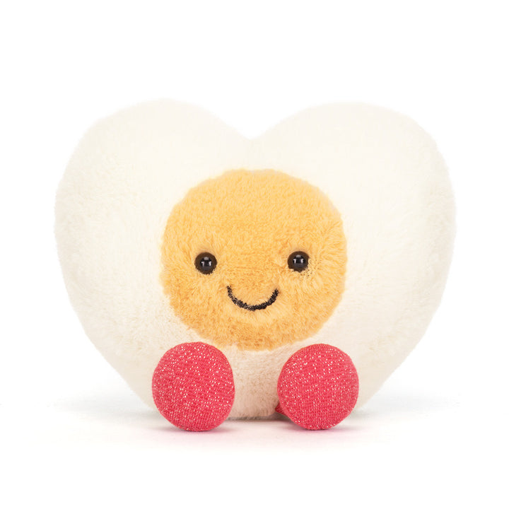Jellycat Amuseables Heart Boiled Egg plush with cream heart shape, yellow center, stitched smile, and pink feet on a white background