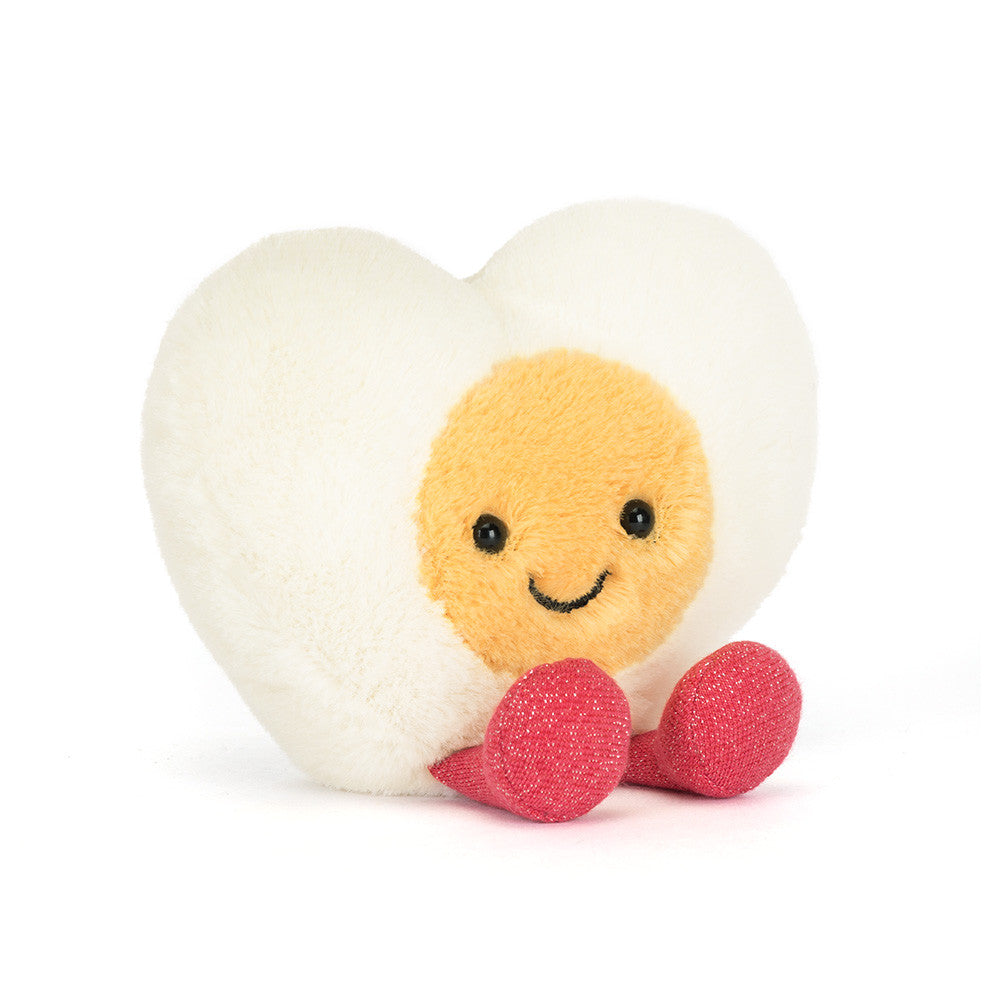 Jellycat Amuseables Heart Boiled Egg plush with cream heart shape, yellow center, stitched smile, and pink feet on a white background