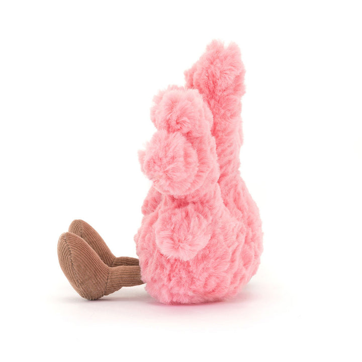 Side view of the Jellycat Amuseable Coral plush toy, showing its textured pink 'branches' from the side and its two corduroy brown feet extended forward on a white background.
