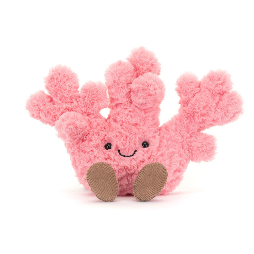 A soft, plush Jellycat Amuseable Coral toy, vibrant pink with a friendly embroidered smile and black eyes, sitting with two corduroy brown feet extended forward, set against a clean white background.