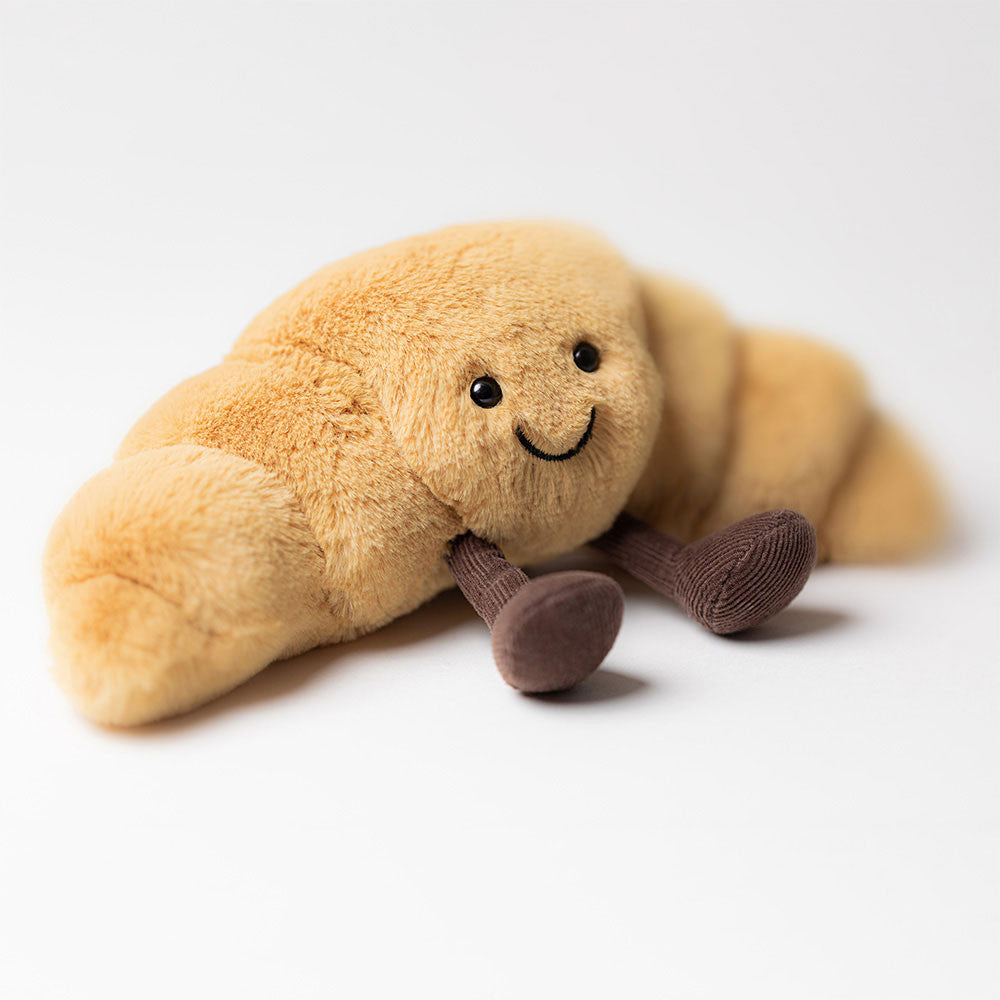 “Amuseables Croissant plush by Jellycat with smiling face and corduroy legs”