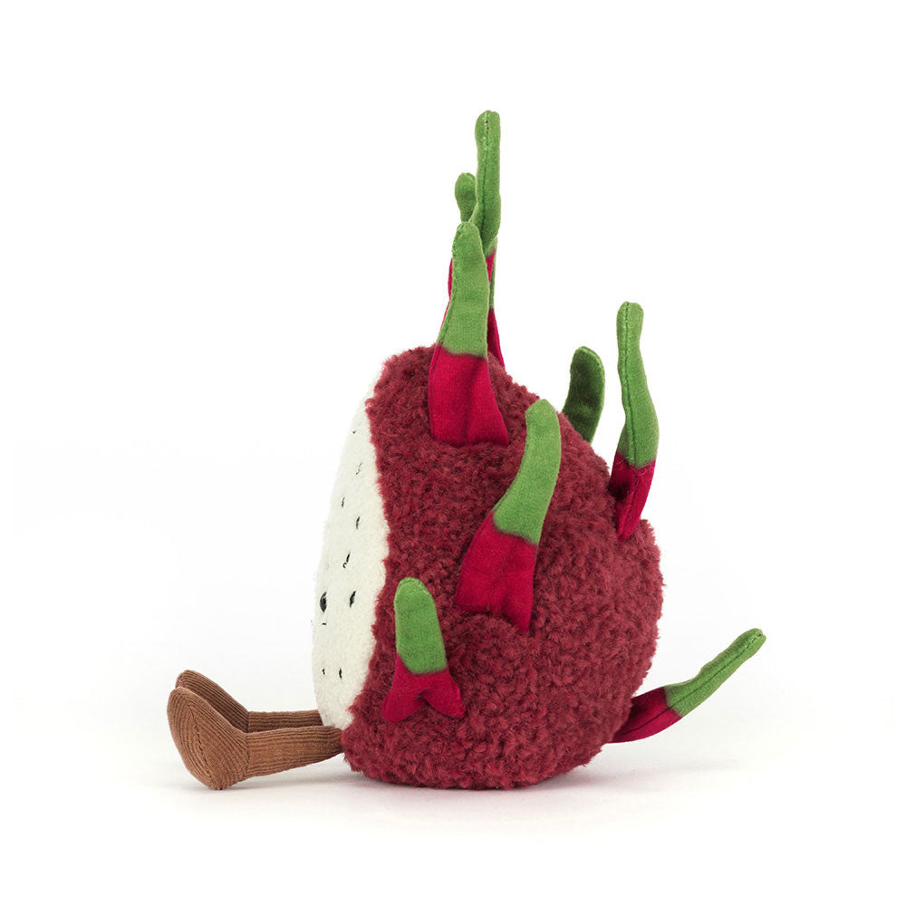 Side profile of the Jellycat Amuseables Dragon Fruit plush, highlighting its thick, textured fuchsia spikes, and a partial view of its white speckled 'flesh' and brown feet outer layer, several pointed green and fuchsia spikes, and a partial view of its white speckled 'flesh' and brown feet.