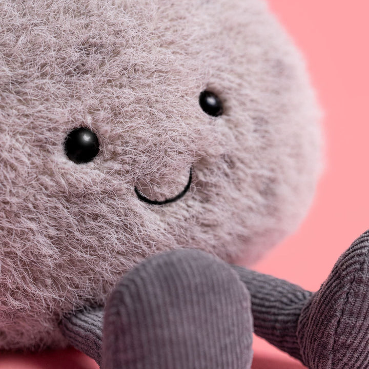 Plush pebble toy with a smiling face on a pink background