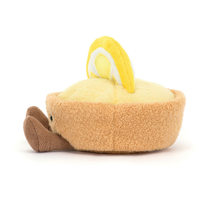 smiling lemon tart plush with golden pastry crust, lemon custard filling, lemon slice topper, and corduroy legs sitting facing left