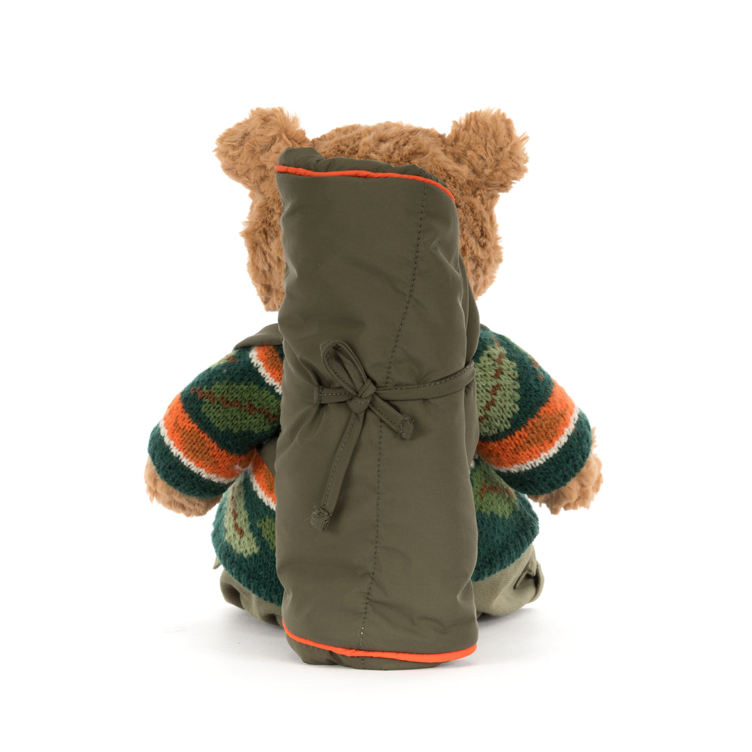 Jellycat Bartholomew Bear Hiking Outfit plush wearing a green woodland sweater, cargo pants, and a camping backpack with a rolled sleeping bag.