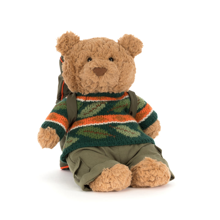 Jellycat Bartholomew Bear Hiking Outfit plush wearing a green woodland sweater, cargo pants, and a camping backpack with a rolled sleeping bag.