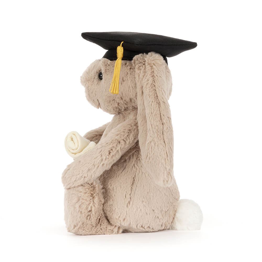 Soft plush bunny wearing graduation cap and holding a diploma. Side view facing left