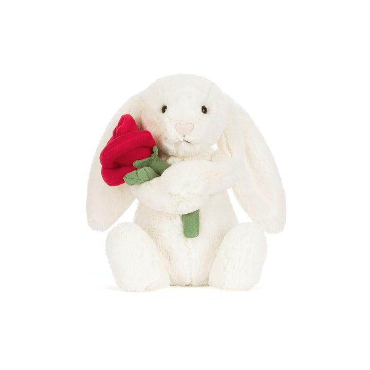 Jellycat Cream Bunny plush holding a red rose with soft cream fur and floppy ears on a white background
