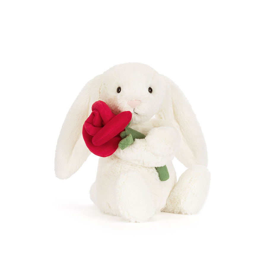 Jellycat Cream Bunny plush holding a red rose with soft cream fur and floppy ears on a white background