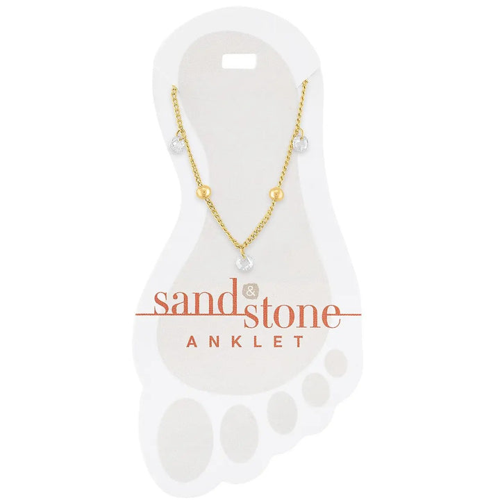 gold stainless steel anklet with bead accents and cubic zirconia dangle charms on a white sand & stone branded card