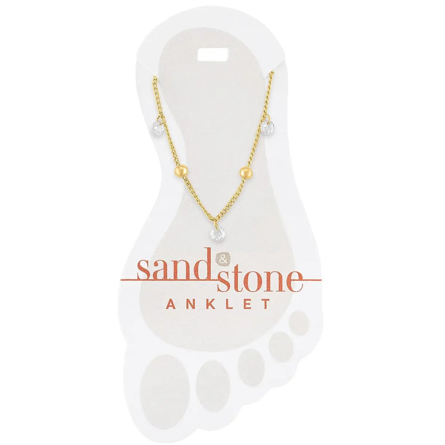 gold stainless steel anklet with bead accents and cubic zirconia dangle charms on a white sand & stone branded card