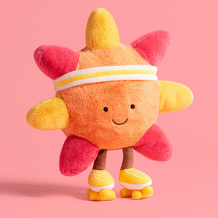 Plush toy amuseable sun with pink ,coral & yellow rays on a pink background