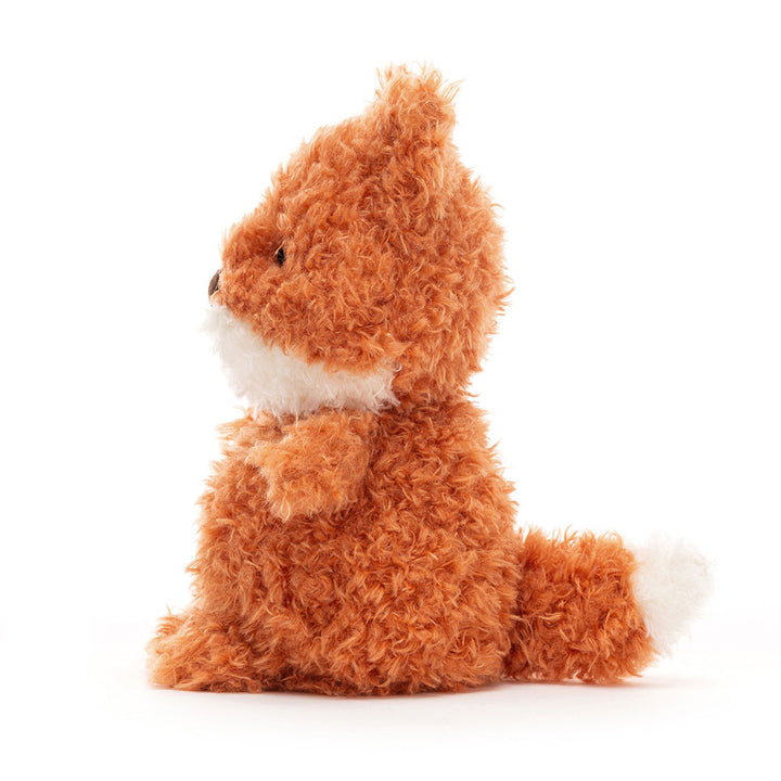 Jellycat Little Fox plush with curly orange fur, white muzzle and tail tip, brown nose, and a sweet embroidered smile sitting sideways facing left on a white background.